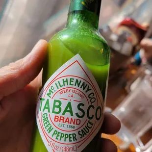 a hand holding a bottle of tabasco