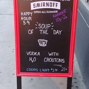 a sign on a sidewalk advertising a cocktail