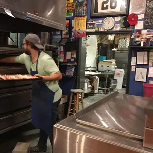 a man putting a pizza into an oven
