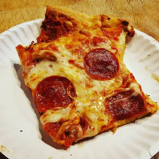a slice of pepperoni pizza on a paper plate