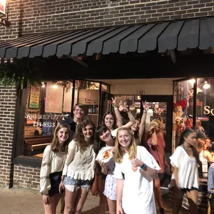 a group of people standing in front of a restaurant