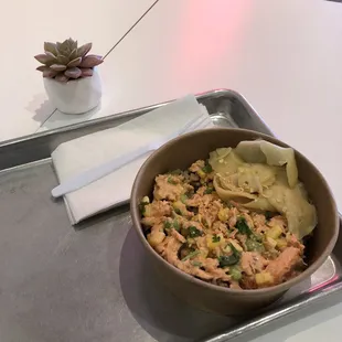 Small bowl of baked salmon, edamame, brown rice, ginger, cilantro, and crisped garlic