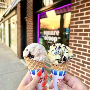 two ice cream cones in front of a brick building