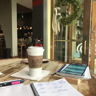 a cup of coffee and notebooks on a table