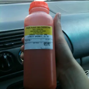 a hand holding a bottle of squash blossom