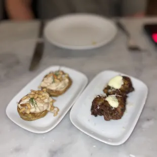 two plates of appetizers on a marble table