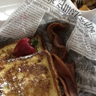 a plate of french toast with bacon and strawberries