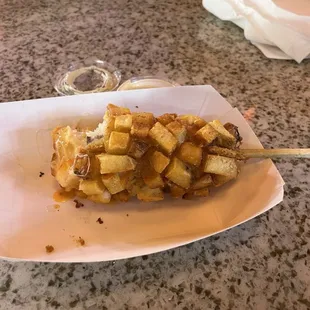 Corn dog with potato bits on parts of hotdogs