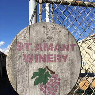 a wooden sign on a chain link fence