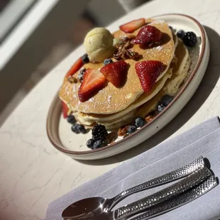 a plate of pancakes with strawberries and blueberries