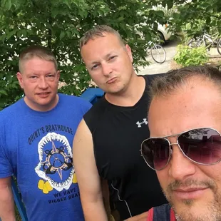 a group of men standing in front of a tree