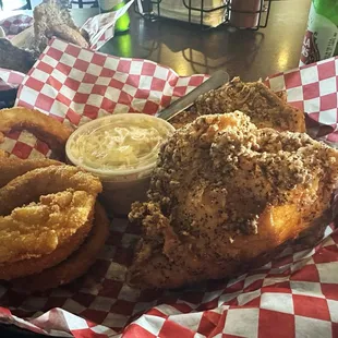 Fried chicken breasts with side of coleslaw and onion rings.