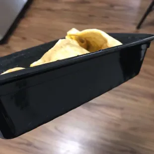 a hand holding a tray of chips