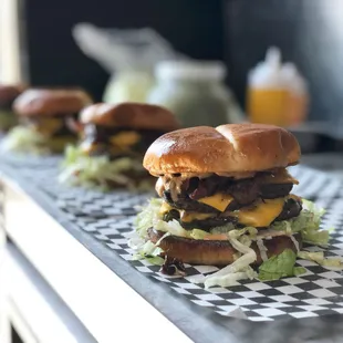 a row of hamburgers with lettuce and cheese