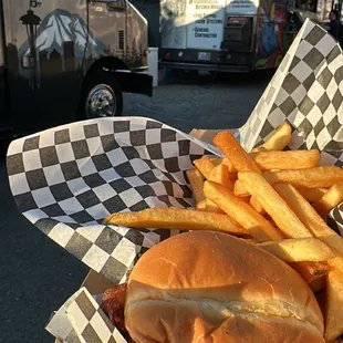 a person holding a basket of food in front of a food truck