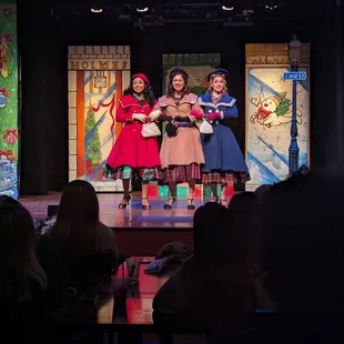 three girls dressed in costumes on stage