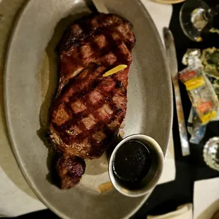a steak on a plate with a side of sauce