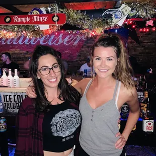 two women standing in front of a bar