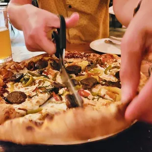 a person cutting a pizza