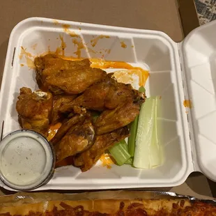 a tray of chicken wings, celery, and dip