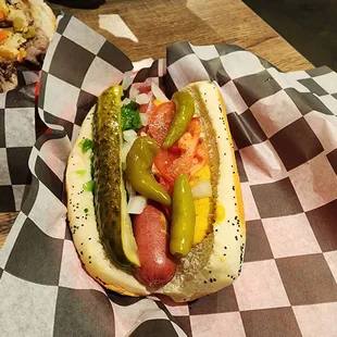 a hot dog with pickles and tomatoes