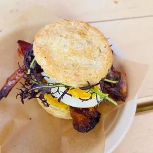 a breakfast sandwich with bacon, egg, and lettuce