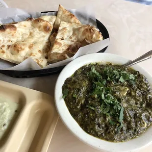 a bowl of spinach and a plate of naan bread