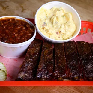a tray of ribs, beans, and pickles