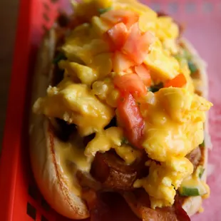 a hot dog with scrambled eggs and bacon