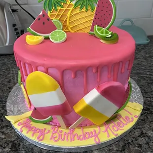 a pink cake decorated with fruit and ice cream