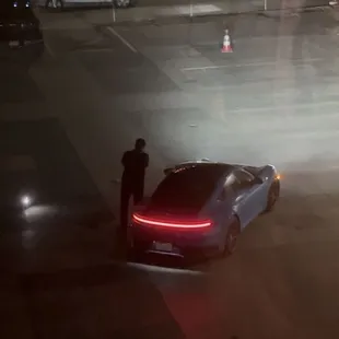 Valet driver propping his phone up and posing with our car