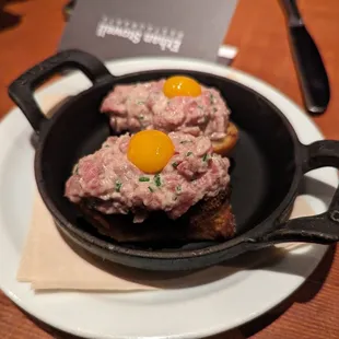 a cast iron skillet with meat and eggs