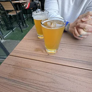 a man sitting at a table with two glasses of beer