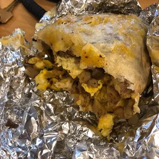 Sausage and egg breakfast burrito with potato and salsa verde