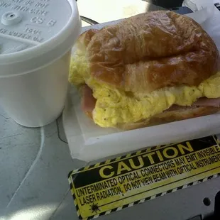 a croissant sandwich and a drink