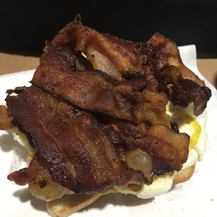 The abundant bacon sandwich with one piece already eaten.