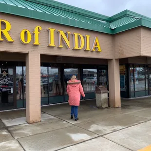 a woman in a pink coat standing in front of a store