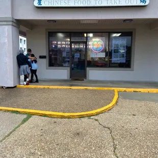 two people standing outside of a restaurant