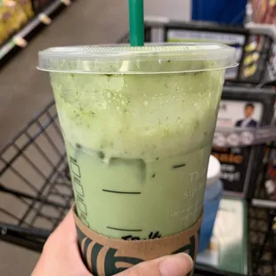 a hand holding a cup of green tea