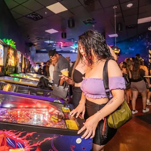 a woman playing a pinball game