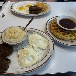 Waffle Platter with eggs over medium, grits with cheese, and sausage.