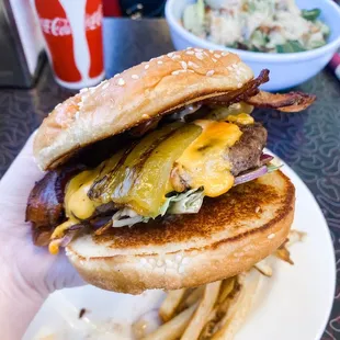 a hand holding a cheeseburger and fries