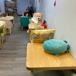 a teddy bear sitting on a table in a children&apos;s playroom