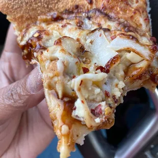 a hand holding a slice of pizza