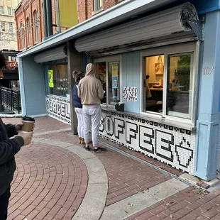 two people standing outside of a coffee shop