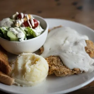 a plate of food including mashed potatoes, bread, and salad