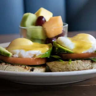 a plate of eggs benedicts and fruit