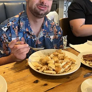 a man sitting at a table with a plate of food in front of him