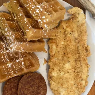 a plate of waffles, pancakes, and sausage