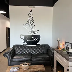 a black leather couch with a cup of coffee on top of it
